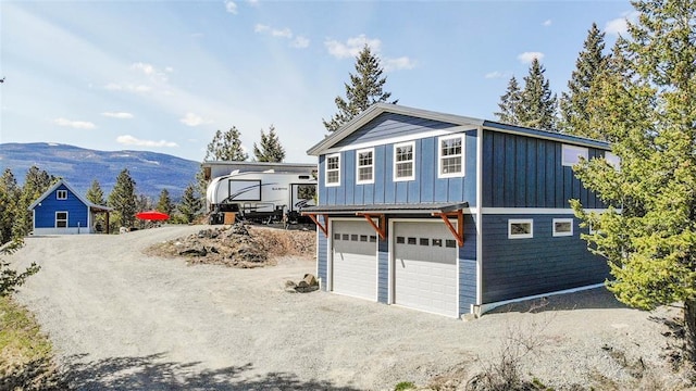 exterior space with a mountain view, an attached garage, board and batten siding, and driveway