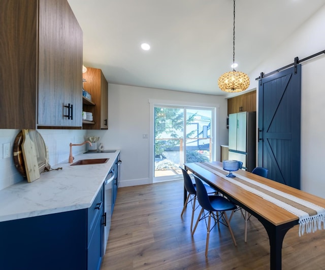 interior space featuring tasteful backsplash, open shelves, a barn door, stainless steel appliances, and a sink