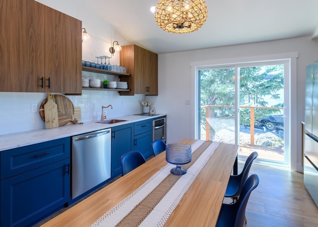 kitchen with open shelves, a sink, stainless steel appliances, light wood-type flooring, and backsplash