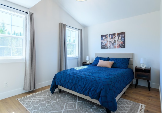 bedroom featuring baseboards, lofted ceiling, and wood finished floors