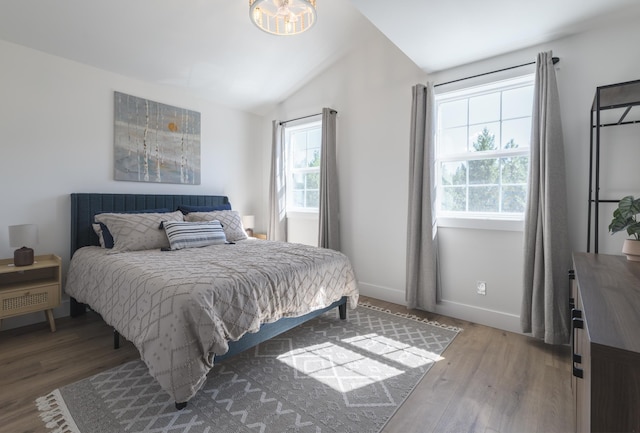 bedroom with multiple windows, lofted ceiling, and wood finished floors