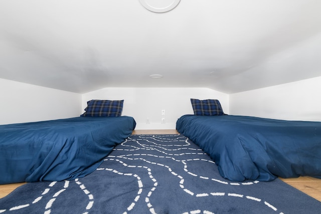 bedroom with wood finished floors and vaulted ceiling