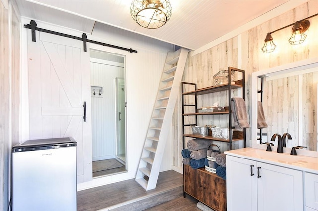 interior space with a barn door, wood finished floors, and wood walls