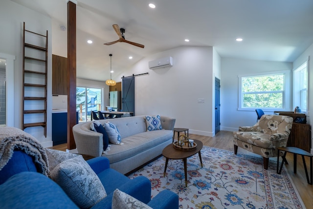 living room featuring light wood-style flooring, recessed lighting, an AC wall unit, vaulted ceiling, and a barn door