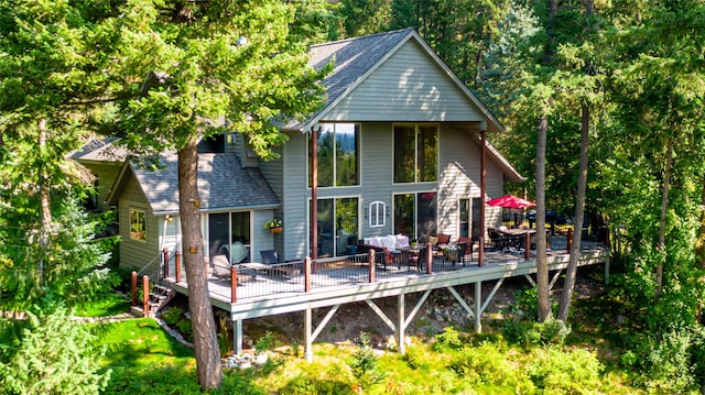 back of property with a deck and roof with shingles