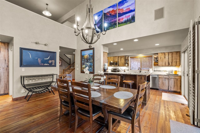 dining area with visible vents, baseboards, light wood-style flooring, a high ceiling, and stairs