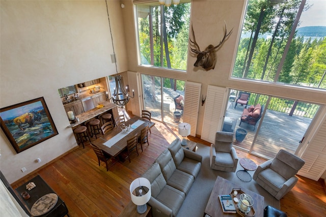 living room with a high ceiling, wood finished floors, and an inviting chandelier