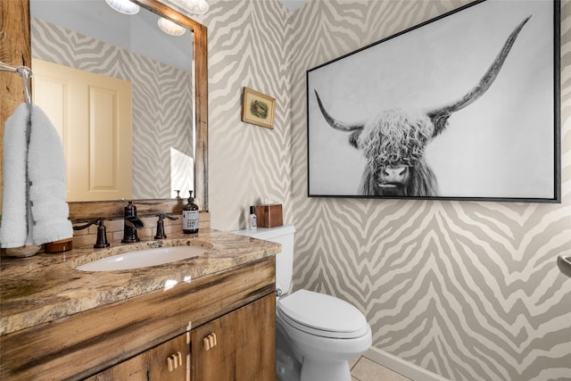 half bathroom featuring tile patterned floors, vanity, toilet, and wallpapered walls