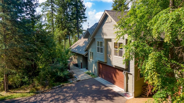 view of front of home featuring aphalt driveway, roof with shingles, and an attached garage