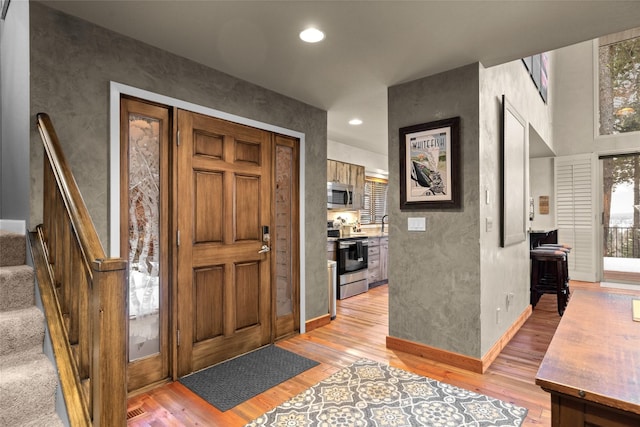 foyer entrance featuring stairway, recessed lighting, light wood-style flooring, and baseboards