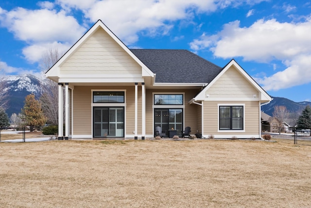 view of front of house with a front lawn, roof with shingles, fence, and a mountain view