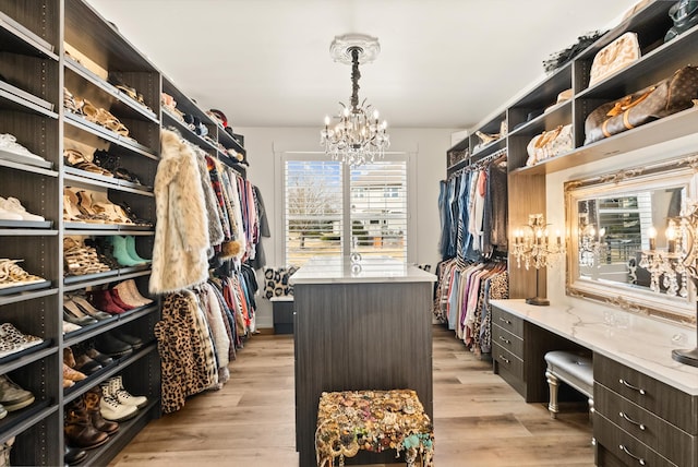 walk in closet featuring a chandelier, built in study area, and light wood-style floors