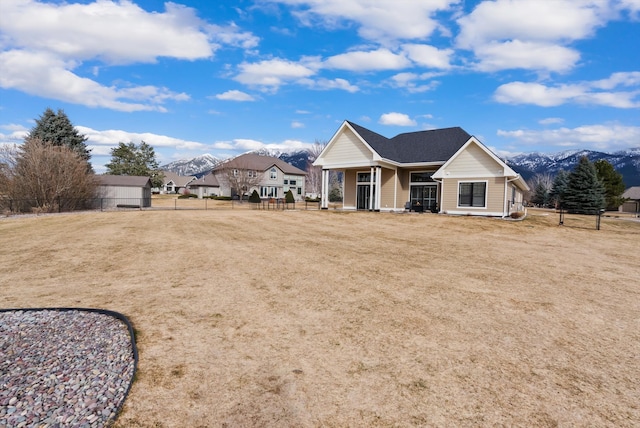 view of front of property featuring a mountain view, a porch, fence, and a front lawn