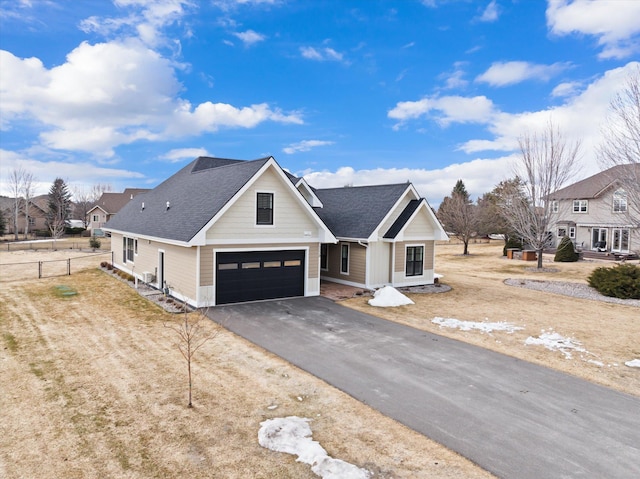 view of front of home featuring a garage, driveway, fence, and a shingled roof