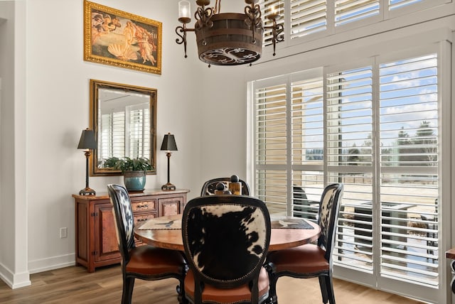 dining room with light wood-style floors, a chandelier, and baseboards