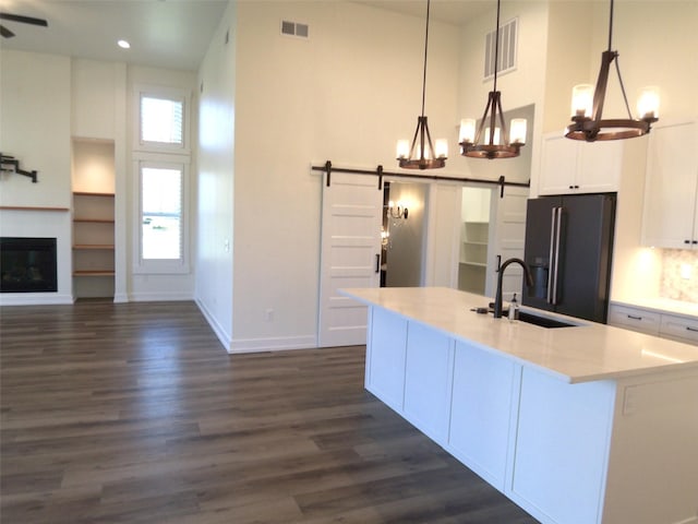 1228 Quail Ridge Dr, Kalispell, MT 59901 - kitchen with black refrigerator with ice dispenser, a barn door, a high ceiling, dark wood-type flooring, and white cabinets