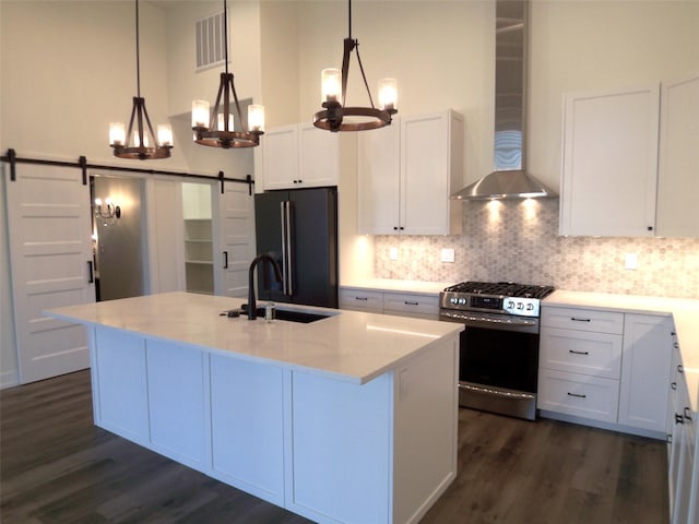 1228 Quail Ridge Dr, Kalispell, MT 59901 - kitchen featuring stainless steel gas range oven, wall chimney exhaust hood, black fridge, a barn door, and a chandelier