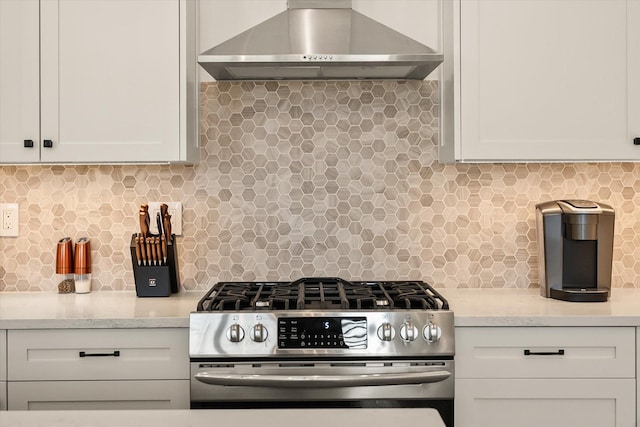 kitchen with white cabinets, stainless steel gas stove, backsplash, and wall chimney exhaust hood