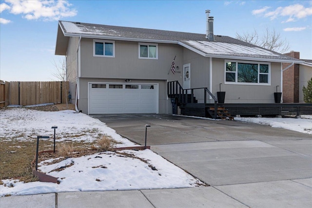 split level home with an attached garage, fence, and concrete driveway