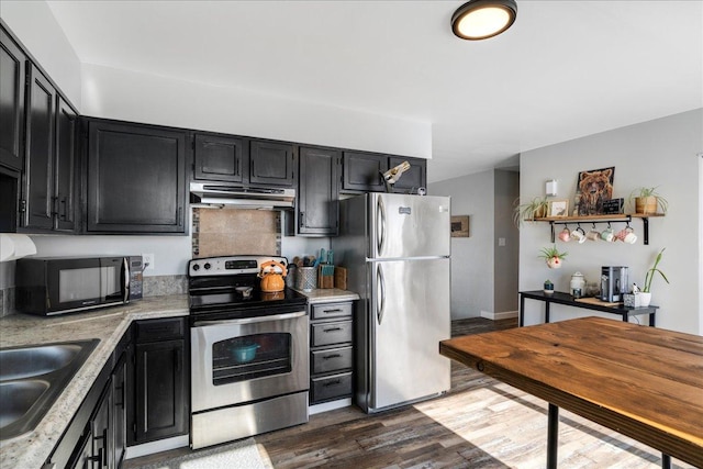 kitchen featuring dark wood finished floors, appliances with stainless steel finishes, a sink, dark cabinets, and under cabinet range hood