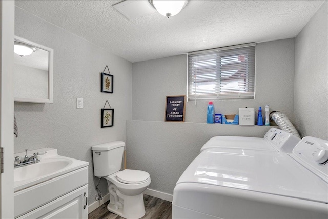 bathroom with a textured wall, toilet, wood finished floors, a textured ceiling, and washing machine and dryer