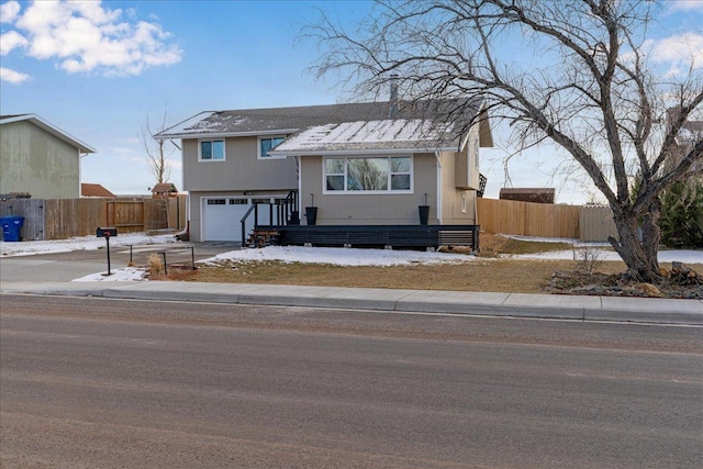 view of front facade with driveway, an attached garage, and fence