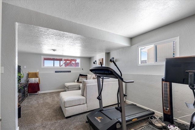 workout area with carpet, a textured wall, a textured ceiling, and baseboards