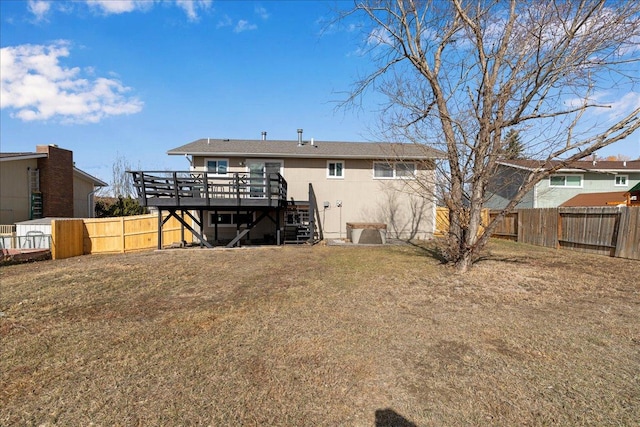 rear view of property featuring a deck, a yard, stairway, and a fenced backyard