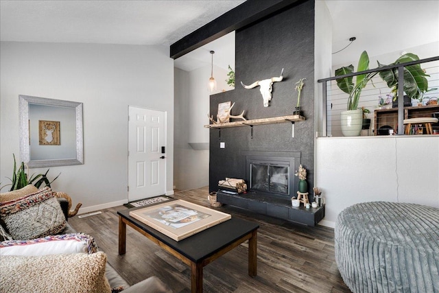 living area with lofted ceiling with beams, a tiled fireplace, wood finished floors, and baseboards