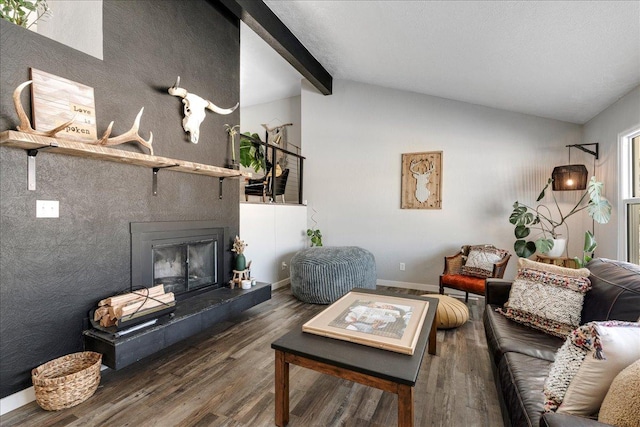 living room featuring vaulted ceiling with beams, a fireplace, baseboards, and wood finished floors