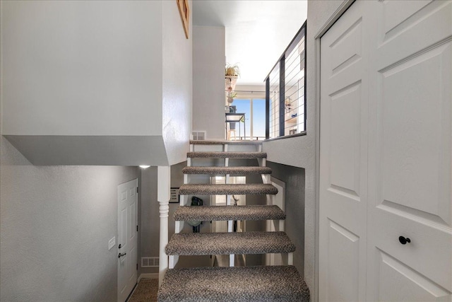 staircase featuring visible vents and a textured wall