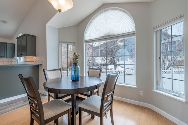 dining space featuring lofted ceiling, light wood-style floors, and baseboards