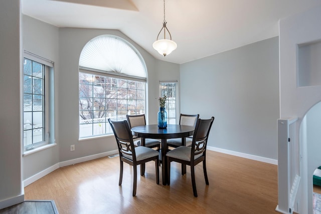 dining space featuring lofted ceiling, baseboards, and wood finished floors