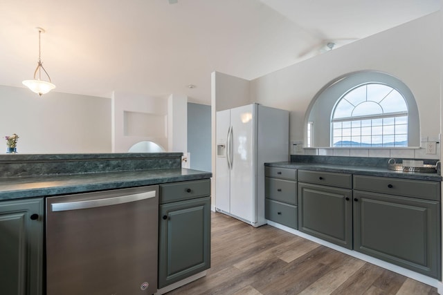 kitchen with dark countertops, white fridge with ice dispenser, and dishwasher