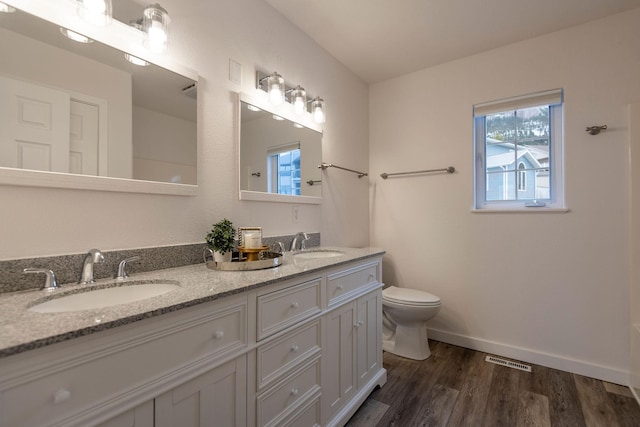 bathroom featuring toilet, wood finished floors, a sink, and visible vents