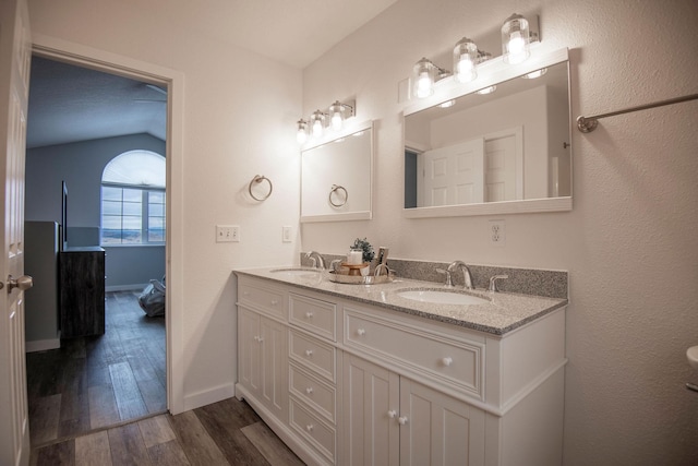 bathroom featuring double vanity, wood finished floors, a sink, and baseboards