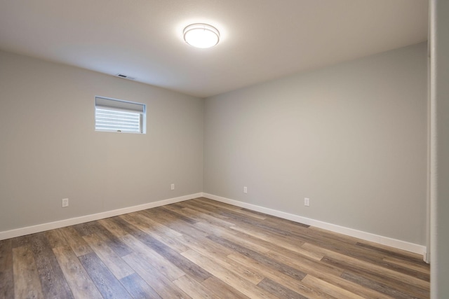 spare room featuring wood finished floors, visible vents, and baseboards