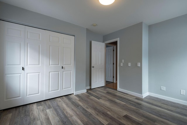 unfurnished bedroom featuring a closet, baseboards, and dark wood-type flooring