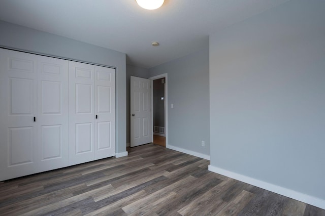 unfurnished bedroom featuring a closet, wood finished floors, and baseboards