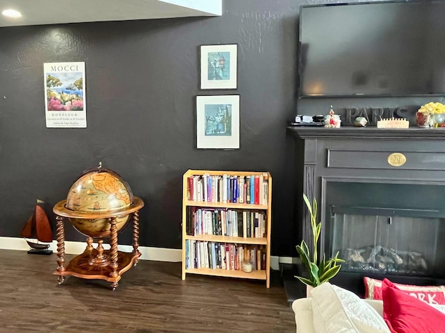 sitting room with a fireplace, baseboards, and wood finished floors