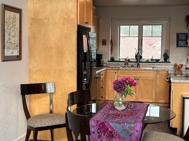 kitchen featuring electric range oven, a textured wall, a sink, and black fridge with ice dispenser