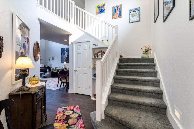 stairway featuring a towering ceiling and wood finished floors