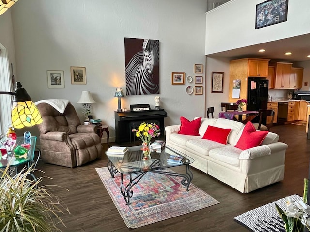 living room with recessed lighting, dark wood finished floors, and a towering ceiling