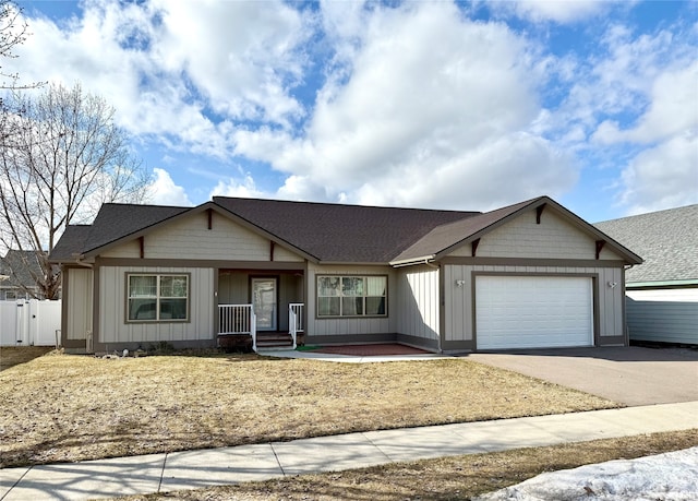 view of front of property featuring board and batten siding, driveway, a garage, and fence