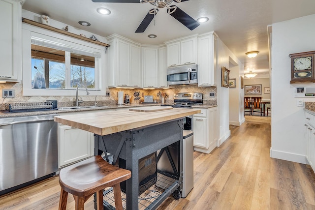 kitchen with a sink, butcher block counters, light wood finished floors, and stainless steel appliances