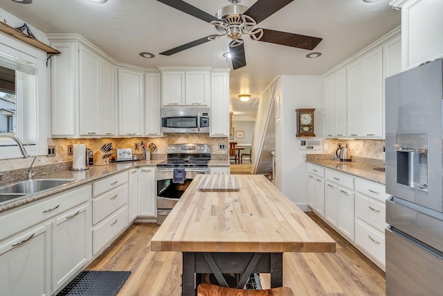 kitchen featuring light wood finished floors, stainless steel appliances, wooden counters, and white cabinetry