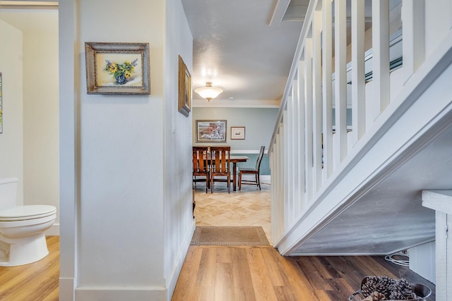 hallway with stairs, crown molding, baseboards, and wood finished floors