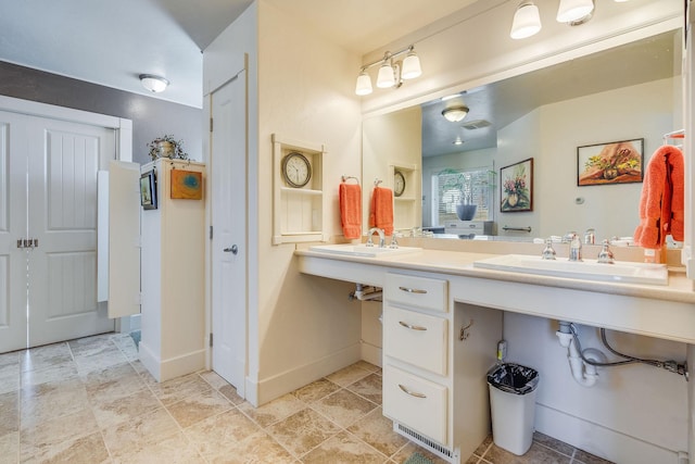 full bath with double vanity, baseboards, and a sink