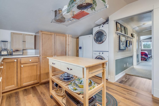 kitchen with light wood finished floors, white refrigerator with ice dispenser, light countertops, and stacked washing maching and dryer