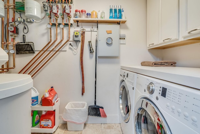 clothes washing area featuring tile patterned flooring, cabinet space, and washer and clothes dryer